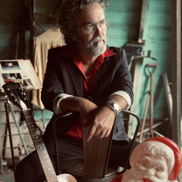 Image of Mark Edgar Stuart with a guitar and plastic Santa Claus