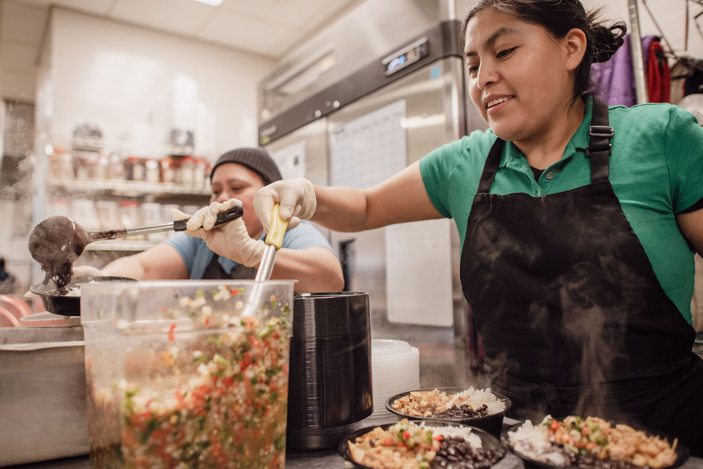 two women making food in a restaurant kitchen